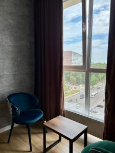 een blauwe stoel en een tafel voor een raam bij Апартаменти в Гранях in Dnipro