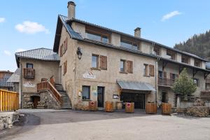 a large stone building with wooden posts in front of it at La Mansio de Bons in Les Deux Alpes