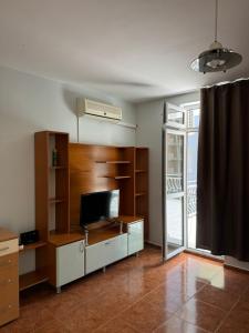 a living room with a tv and a large window at Апартамент Александър in Sunny Beach