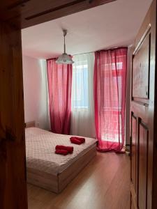 a bedroom with a bed with red pillows on it at Апартамент Александър in Sunny Beach