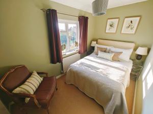 King Arthur's Rest House, Hot Tub & Garden Sleeps 10 في South Cadbury: غرفة نوم بها سرير وكرسي ونافذة
