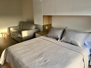 a bedroom with a large bed and a chair at DF Acogedor Loft con Gym D02 in Bogotá