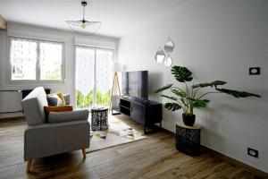 a living room with a chair and a television at La Tardiere #Confort#Calme in Clermont-Ferrand