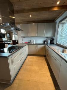 a kitchen with white cabinets and a tile floor at Myrkdalen Lodge II, luxury family cabin in Helgatun