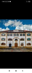 瓜塔维塔Hotel El Dorado Guatavita的一座白色的大建筑,背后是天空
