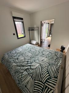 a bedroom with a bed with a black and white comforter at Cottage bungalow le St Vel' in Velennes