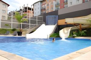 a woman swimming in a swimming pool with a slide at Apto em Rio Quente com ampla área de lazer e linda vista in Rio Quente