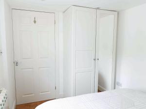 ein weißes Schlafzimmer mit weißen Schranktüren und einem Bett in der Unterkunft The Pool House in Tywardreath