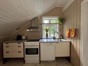 a kitchen with a sink and a stove and a window at Cosy cabin in Risør in Risør