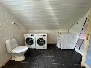 a small bathroom with a washing machine and a toilet at Cosy cabin in Risør in Risør