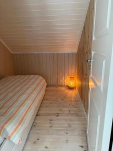 a small room with a bed and a lamp at Cosy cabin in Risør in Risør