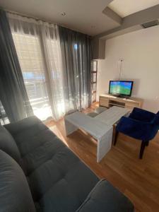 a living room with a couch and a flat screen tv at Lux In A Box, Apartments In the center in Nea Kallikrateia