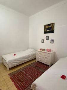 a room with two beds and a dresser in it at Maison Mina in Oualidia