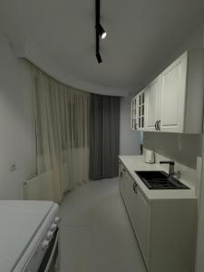 a white kitchen with a sink and a stove at Art Apartment 2 in Prishtinë
