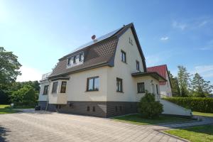 ein weißes Haus mit einem schwarzen Dach und einer Auffahrt in der Unterkunft Ferienhaus in Brandenburg an der Havel in Brandenburg an der Havel