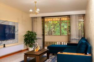 a living room with a blue couch and a large window at Blissful Homes in Kampala