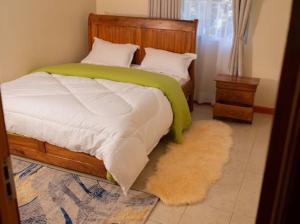 a bedroom with a bed with a green blanket at Blissful Homes in Kampala