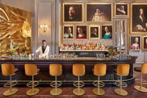 a man standing behind a bar in a room with portraits at Mandarin Oriental Ritz, Madrid in Madrid +73 photos