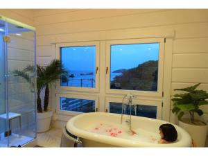 a woman sitting in a bath tub in a bathroom at Hotel Shiki no Kura - Vacation STAY 29695v in Kawazu +29 photos