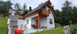 a small white house with a wooden roof at Domek Pod Lasem in Lipowa