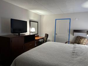 a hotel room with a bed and a flat screen tv at American Inn & Suites Bishop Airport Flint in Flint