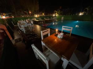 a table and chairs next to a swimming pool at night at Art Resort Goa in Palolem