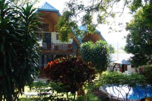 a house with a balcony and a yard with trees at Princess of Coron Austrian Resort in Coron