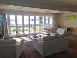 a living room with couches and a view of the ocean at Kingsgate Hotel Autolodge Paihia in Paihia