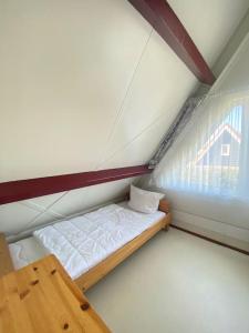 a small bed in a room with a window at Strandnah am Meer für die ganze Familie in Oostkapelle