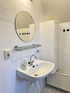 a white bathroom with a sink and a mirror at Strandnah am Meer für die ganze Familie in Oostkapelle +21 photos