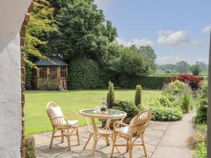 a patio with a table and chairs in a garden at Chestnuts at Youlton Lodge in York