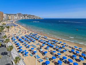 - une plage avec des parasols bleus et l'océan dans l'établissement Barceló Benidorm Beach - Adults Recommended, à Benidorm
