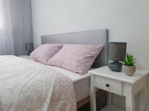 Cama blanca con almohada rosa y mesita de noche en Casa Victor, en San Pedro del Pinatar