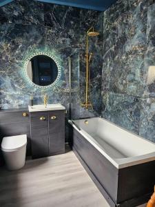 a bathroom with a tub and a toilet and a sink at Jubilee Jem in Aberaman