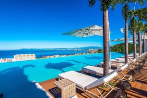 a swimming pool with chairs and an umbrella at SOHO PV - 1007 Best and Brand New Condo in Puerto Vallarta +5 photos
