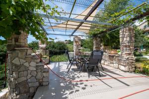 a patio with a table and chairs and a stone wall at Family friendly house with a swimming pool Radovin, Zadar - 21307 in Ražanac