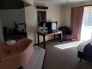 a hotel room with a tub and a bed and a television at Balranald Motor Inn in Balranald