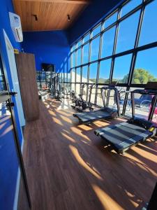 Apartamento com jacuzzi privativa no Wanderlust Hotel في كامبوس دو جورداو: صالة ألعاب رياضية بها صف من أجهزة المشي في غرفة بها نوافذ