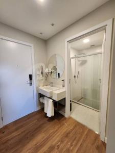 Apartamento com jacuzzi privativa no Wanderlust Hotel في كامبوس دو جورداو: حمام مع حوض ودش ومرآة