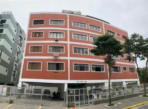 a large red building with a tree in front of it at ESD01- Ar Condicionado 5min a pé da Praia da Enseada, Apartamento in Guarujá