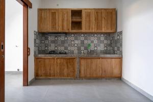 a kitchen with wooden cabinets and a tile wall at Beatrix Villa in Ubud