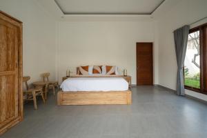 a bedroom with a bed and a table and a window at Beatrix Villa in Ubud