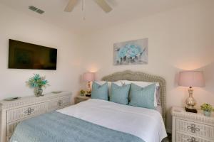a bedroom with a bed with blue pillows and a tv at Beautiful Port St Lucie Home with Hot Tub! in Port Saint Lucie