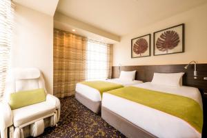 a hotel room with two beds and a chair at remm Hibiya in Tokyo