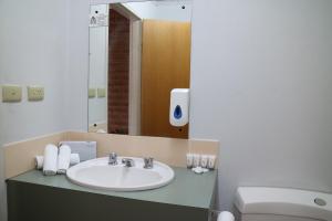 a bathroom with a sink and a toilet and a mirror at Corowa Golf Club Motel in Corowa +43 photos