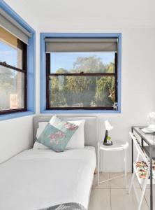 a living room with a white couch and two windows at Modern Single Room - Nearby Stations & Eateries - Shared Bathroom in Blacktown