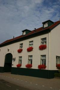 a white building with red flowers in window boxes at 't Reijmerhöfke in Reijmerstok