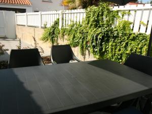 a black table and chairs in front of a fence at Maison rénovée 2 ch, terrasse, proche plage et centre, parking, équipements complets, animaux ok - FR-1-22-356 in La Tranche-sur-Mer