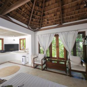 a bedroom with a bed and chairs and windows at The Hip House Villa Phuket in Ban Bang Khu +63 photos