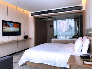 a hotel room with a bed and a television at Paco Hotel Guangzhou Baiyun Airport Liantang Metro in Huadu